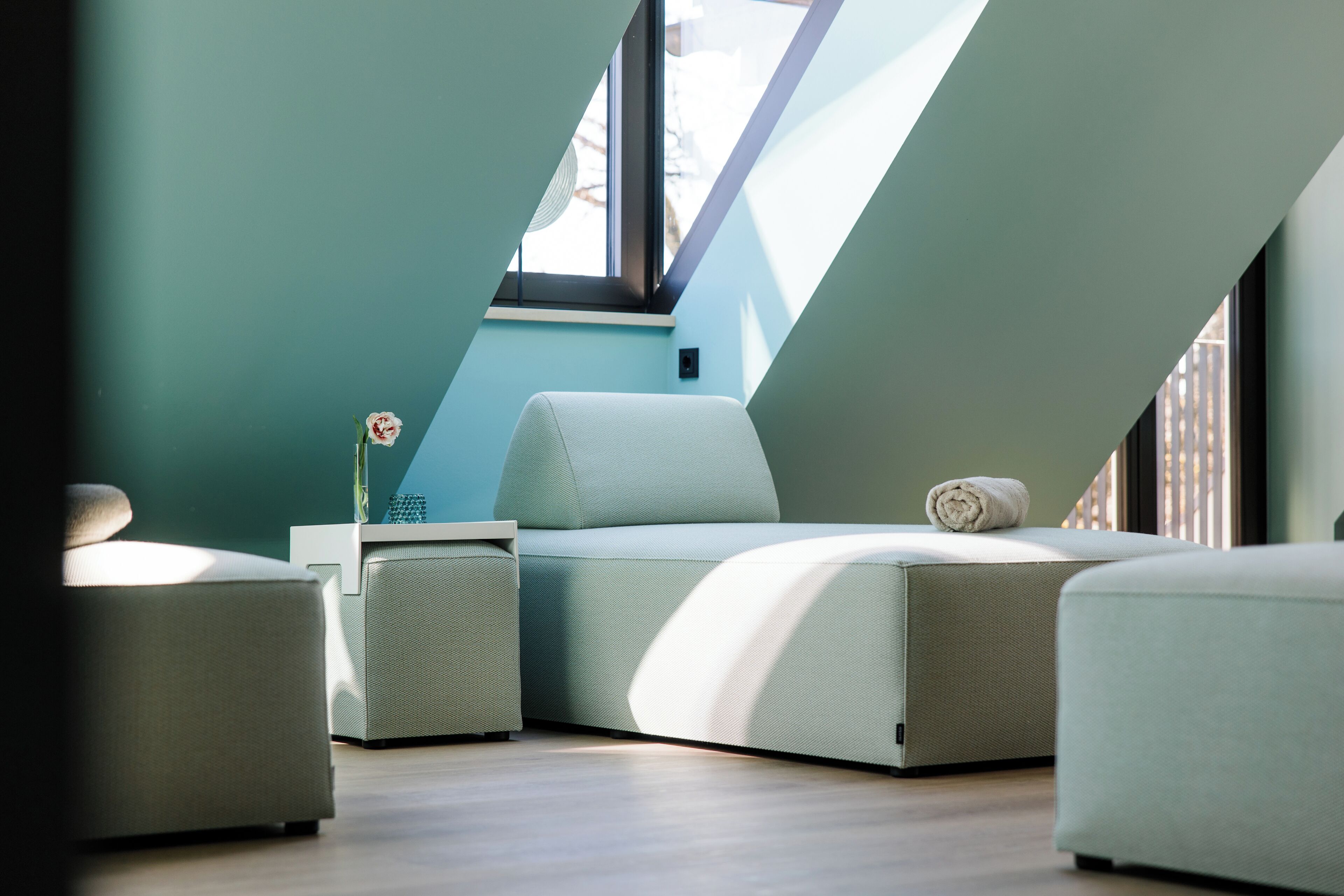 Ein modernes Schlafzimmer im Loft-Stil mit Oberlicht, Schlafsofa, Nachttisch und einer kleinen Pflanze.