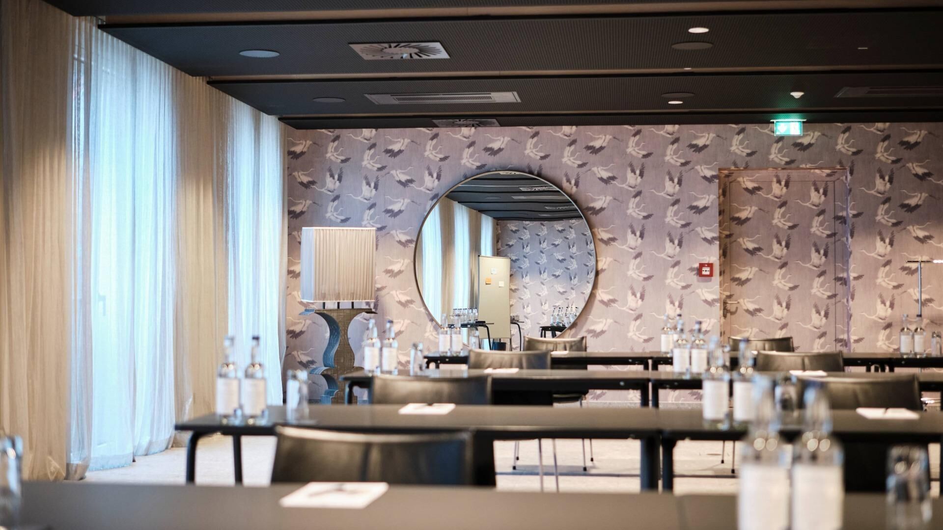 A hotel room with a large mirror, a round table, and a seating area with chairs.