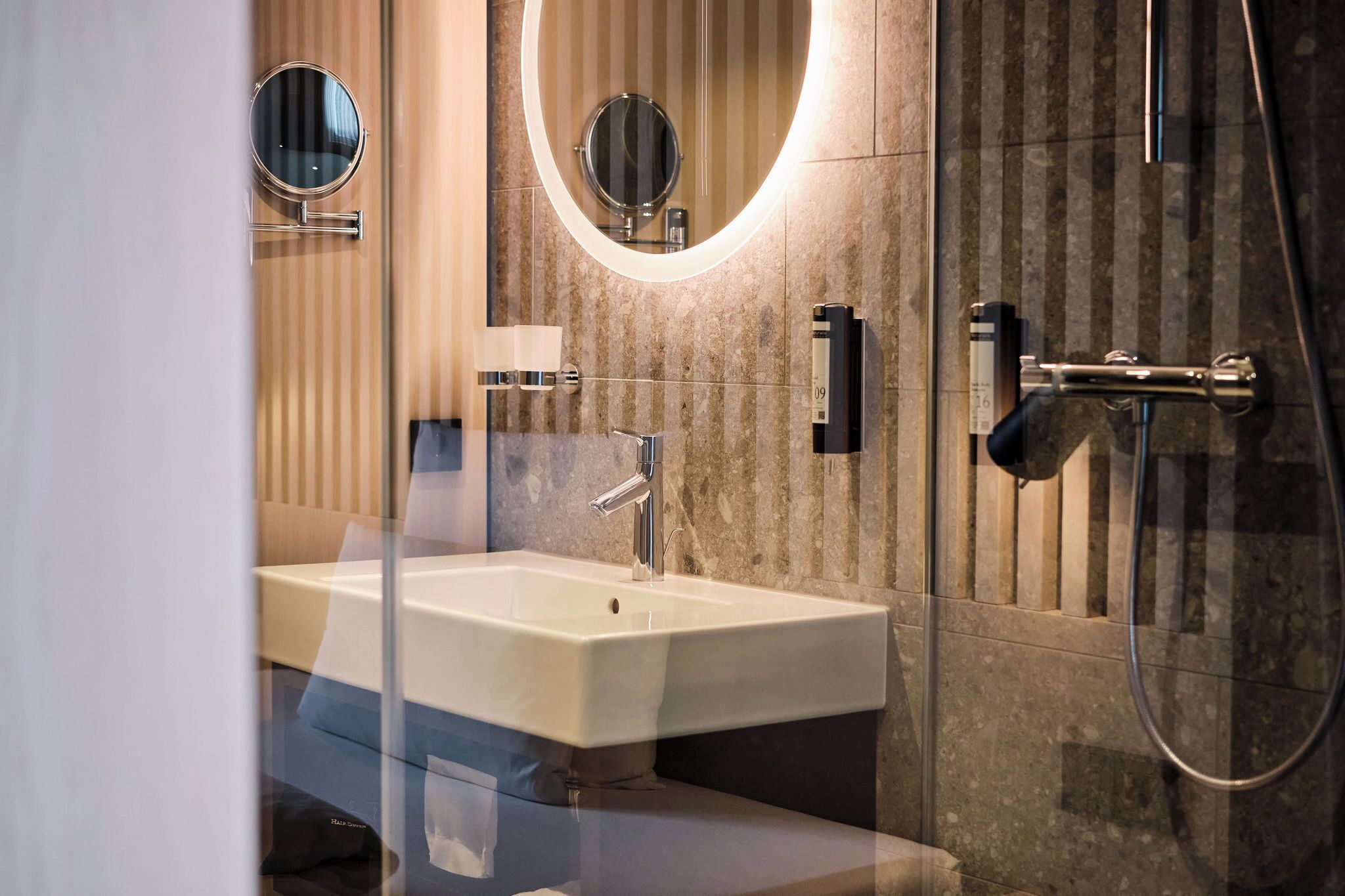 Un bany modern amb un lavabo gran, dos miralls penjats a la paret, un braç de dutxa i un suport per a tovalloles.
