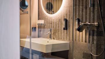Un bany modern amb un lavabo gran, dos miralls penjats a la paret, un braç de dutxa i un suport per a tovalloles.