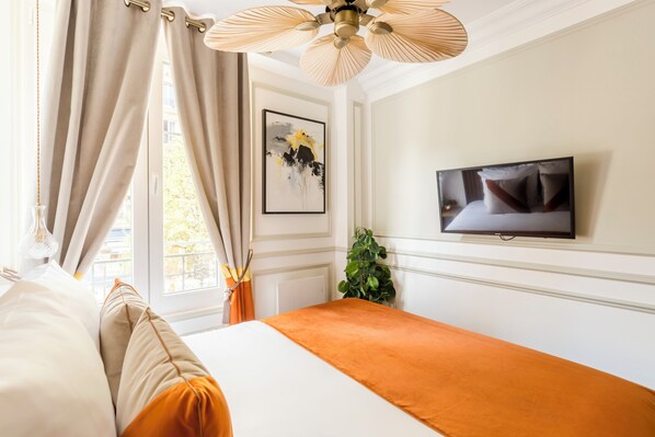 A hotel room with a bed, a television on the wall, and a window with curtains. - Merveil Luxury Suite - Notre Dame -Monge (Paris)