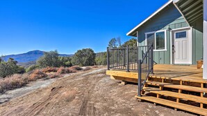 A wooden deck with a metal railing, a door with a window, and a view of a mountainous landscape. - Charming Oakhurst Retreat Near Yosemite, Bass Lake (Oakhurst)