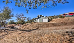 A single-story building with a garage, surrounded by dry vegetation and a clear blue sky.