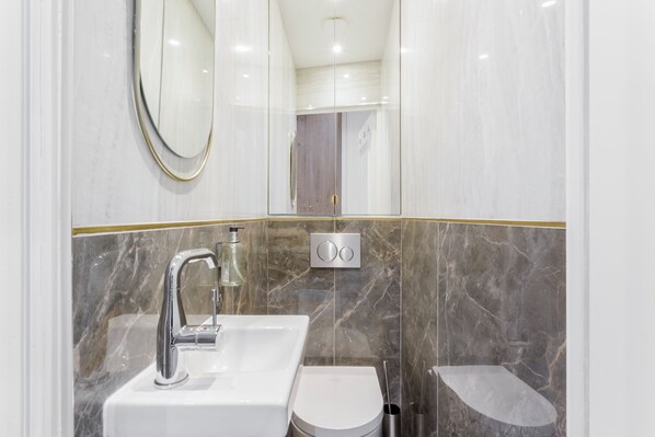 A modern bathroom with a white sink, a mirror, and a toilet. - Merveil Luxury Suite - Marais Republique (Paris)