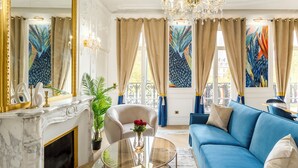 Un salon luxueux avec une cheminée en marbre, un canapé bleu et un lustre.
