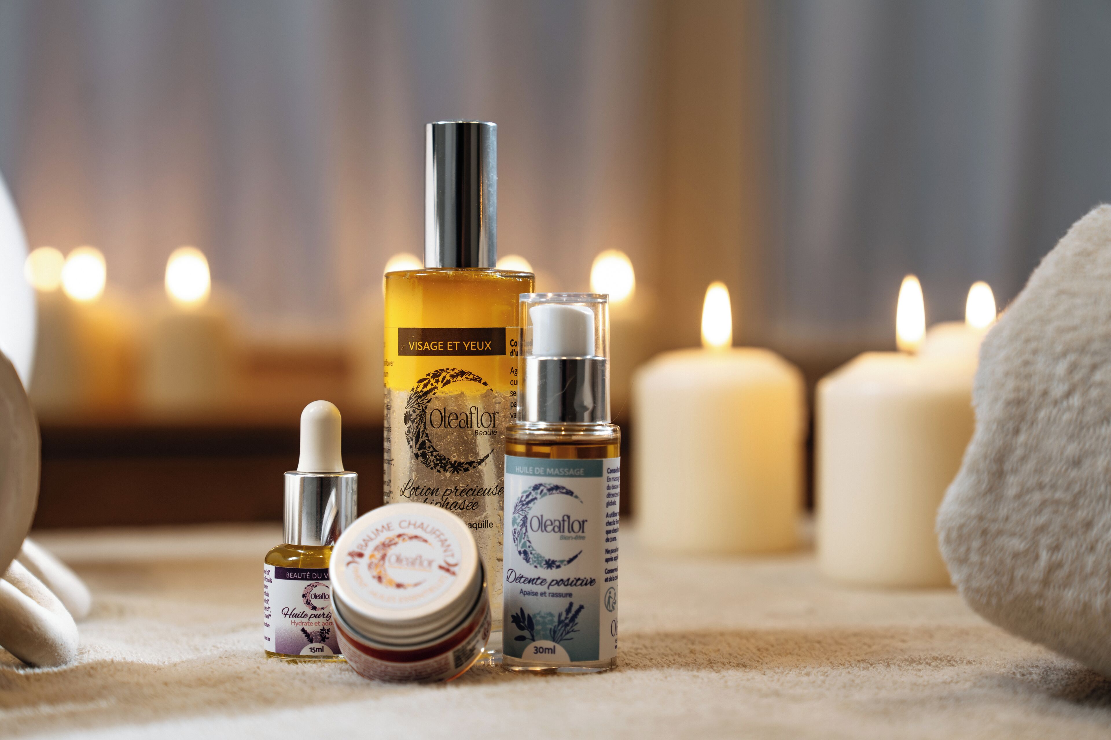 Diversos productos para el cuidado de la piel dispuestos sobre una superficie, con velas al fondo.