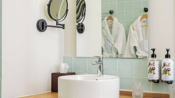 A bathroom with a white sink, two wall-mounted mirrors, a large mirror, and two bottles of hand soap.