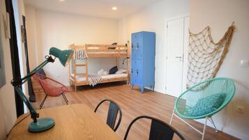 A bunk bed, a desk with a lamp, a chair, a wardrobe, and a hammock.