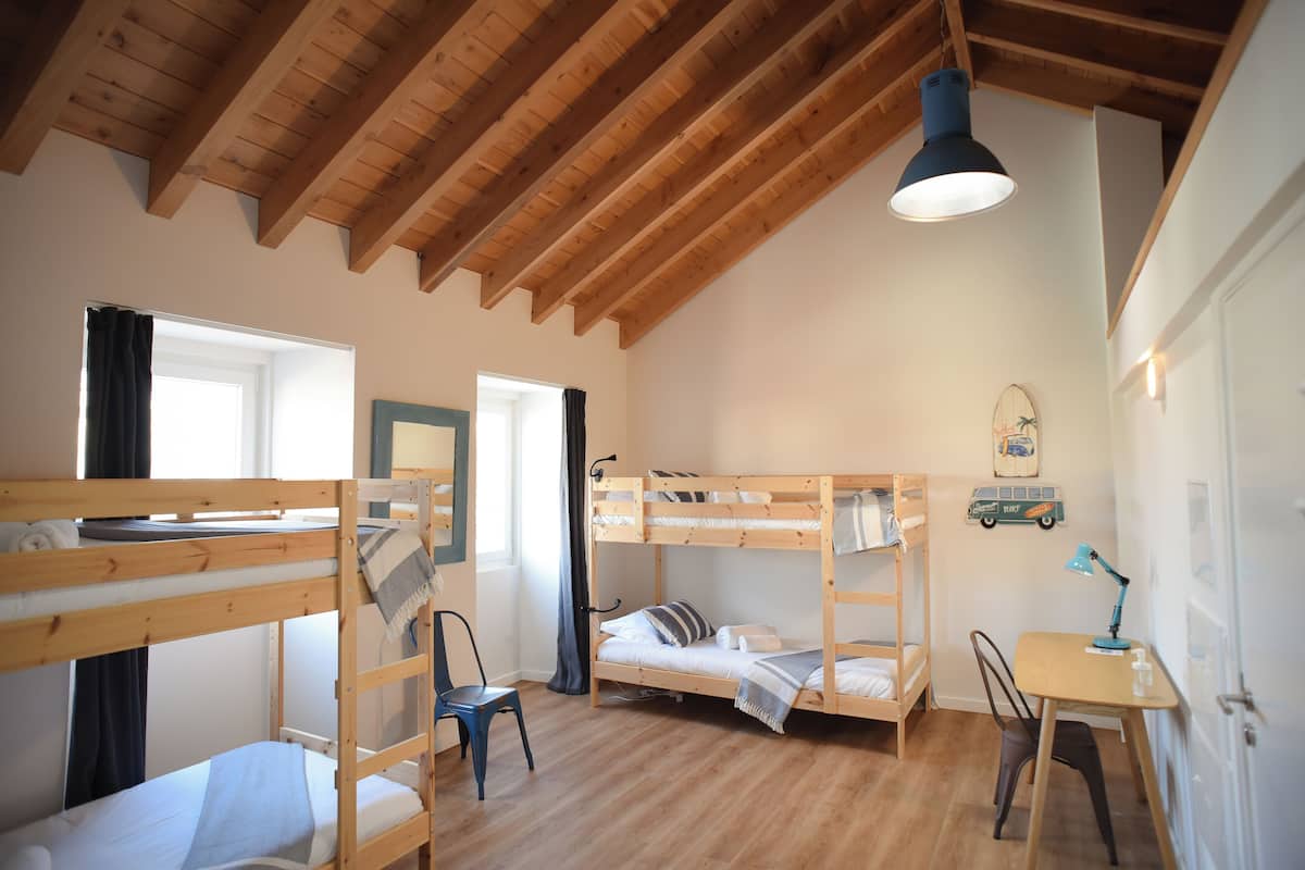 A room with bunk beds, a desk, a chair, a lamp, and a window.