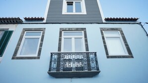 A two-story building with a balcony and two windows on the ground floor. - largobispohostel (Horta)