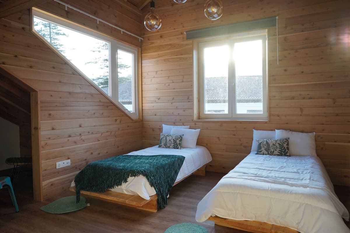 A cabin with two beds, wooden walls, and large windows.