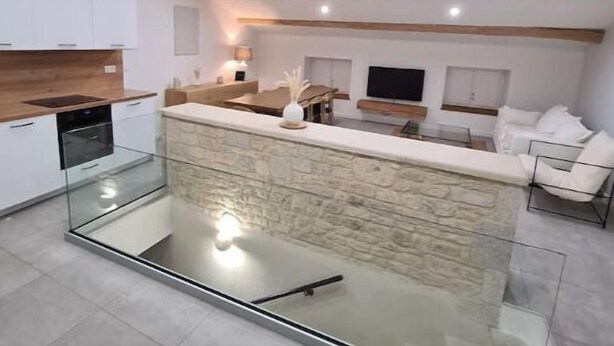 A modern kitchen with a glass island, white cabinets, and exposed wooden beams. - THE ROOFTOP PROVENÇAL (Taulignan)