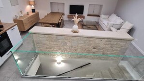 A modern kitchen with a glass island, wooden beams, and a stone backsplash. - THE ROOFTOP PROVENÇAL (Taulignan)