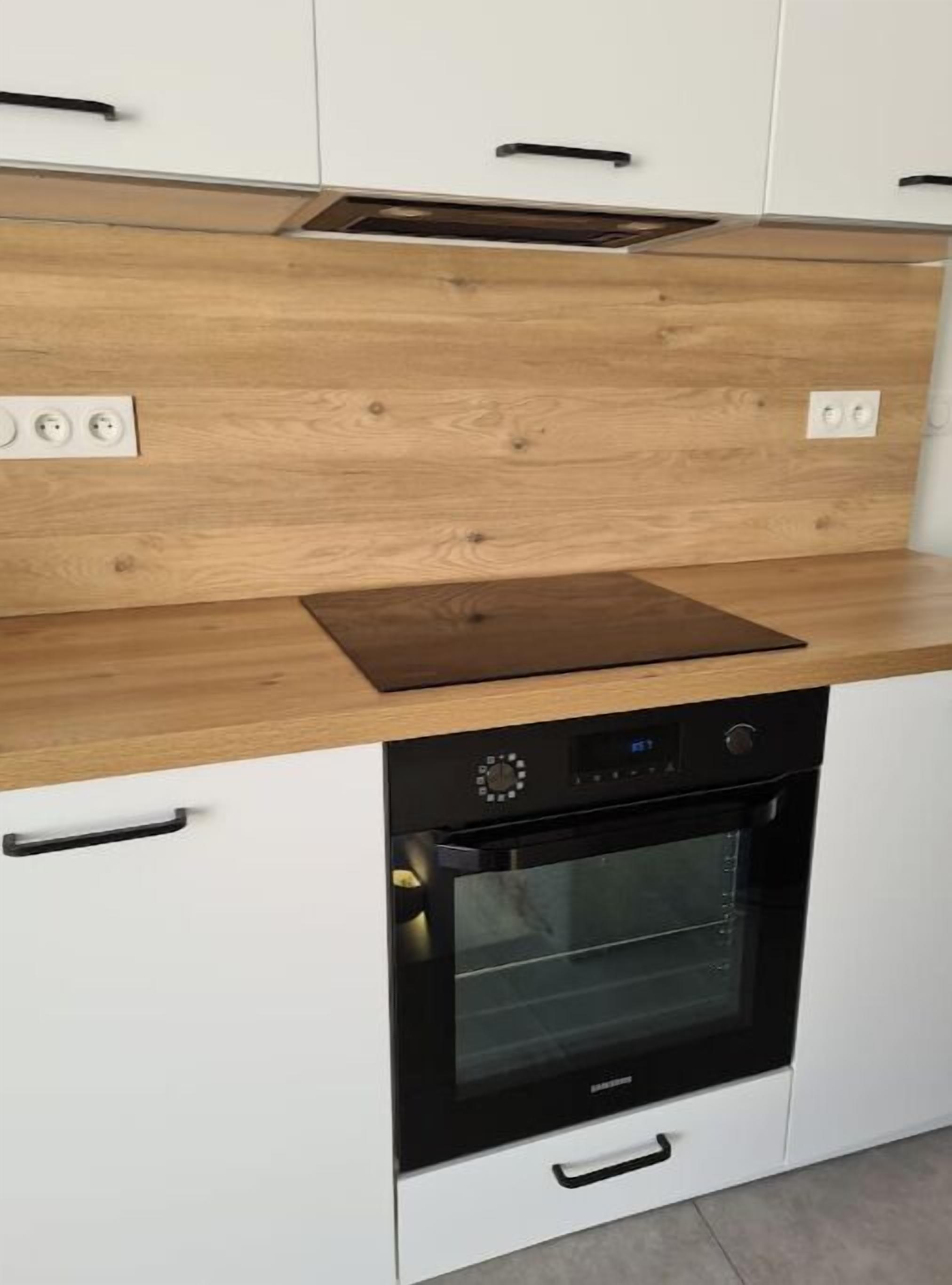 A kitchen with a built-in oven, a wooden countertop, and white cabinets.