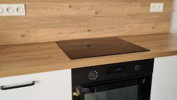 A kitchen with a built-in oven, a wooden countertop, and white cabinets.