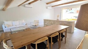 A dining area with a wooden table and chairs, a stone accent wall, and a view of the outside. - THE ROOFTOP PROVENÇAL (Taulignan)