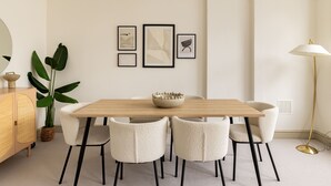 A dining area with a wooden table, six chairs, a bowl, and framed artwork on the wall. - Stylish West Kensington Duplex (London)