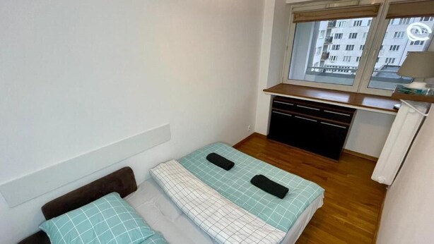 A small, compact room with a bed, a desk, and a window.