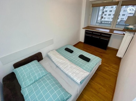A small, compact room with a bed, a desk, and a window.