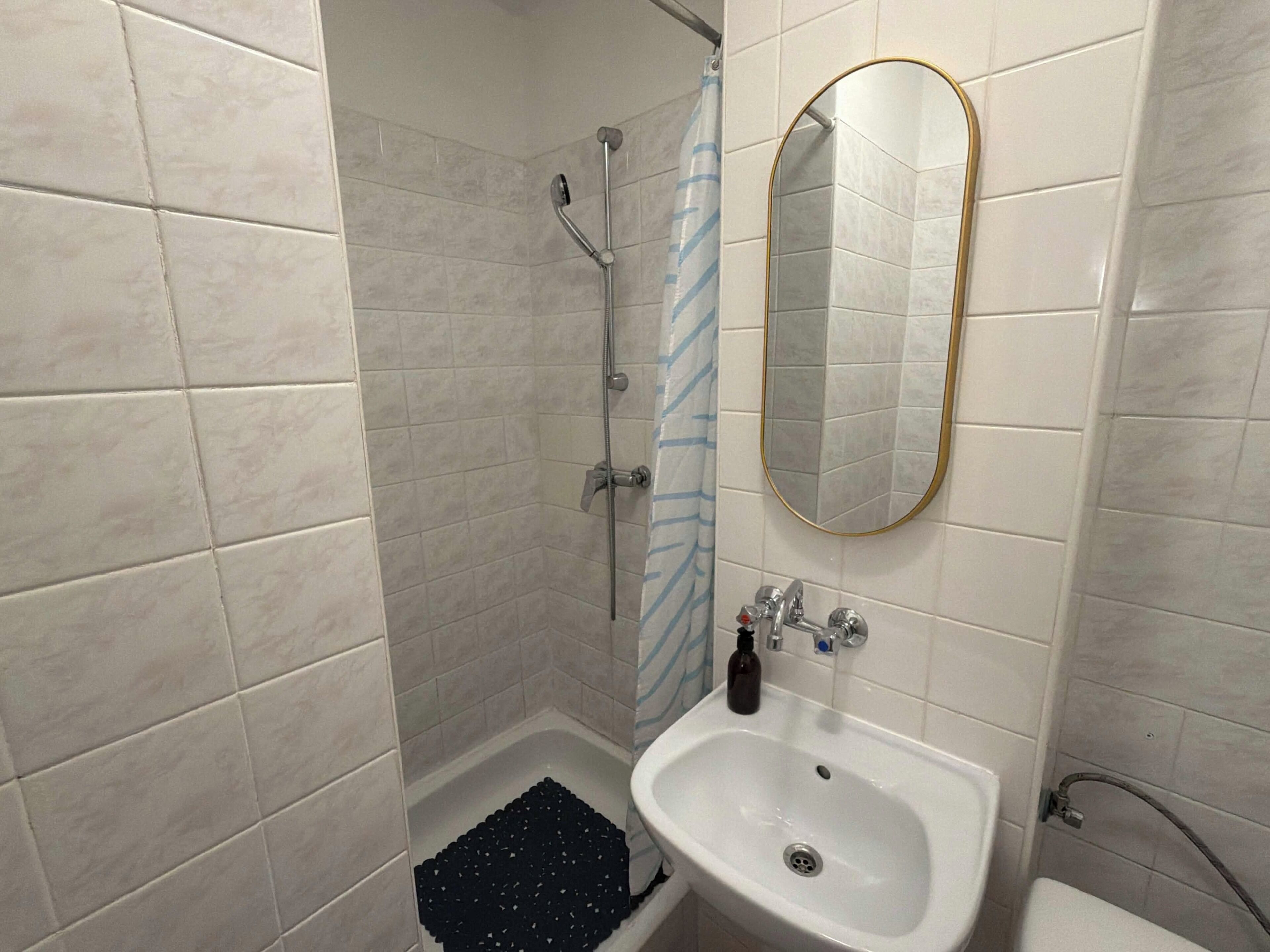 Ein Badezimmer mit Dusche, Waschbecken und Spiegel.