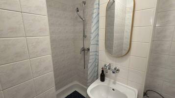 Ein Badezimmer mit Dusche, Waschbecken und Spiegel.