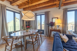 A room with a wooden ceiling, a round dining table with chairs, a sofa, and large windows with curtains. - Holiday Home 'Río Tío Cocinas' with Mountain Views, Balcony and Wi-Fi (Real Sitio de San Ildefonso)