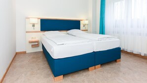 A double bed with a blue headboard, white bedding, and two bedside tables with lamps. - Ferienwohnung fur bis zu 3 Personen in Bensersiel (Esens)