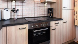 A modern kitchen with a black countertop, stainless steel appliances, and light wood cabinetry. - Ferienwohnung fur bis zu 3 Personen in Bensersiel (Esens)