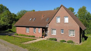 A two-story brick house with a sloped roof, multiple windows, and a small porch area. - Ferienwohnung fur bis zu 3 Personen in Bensersiel (Esens)