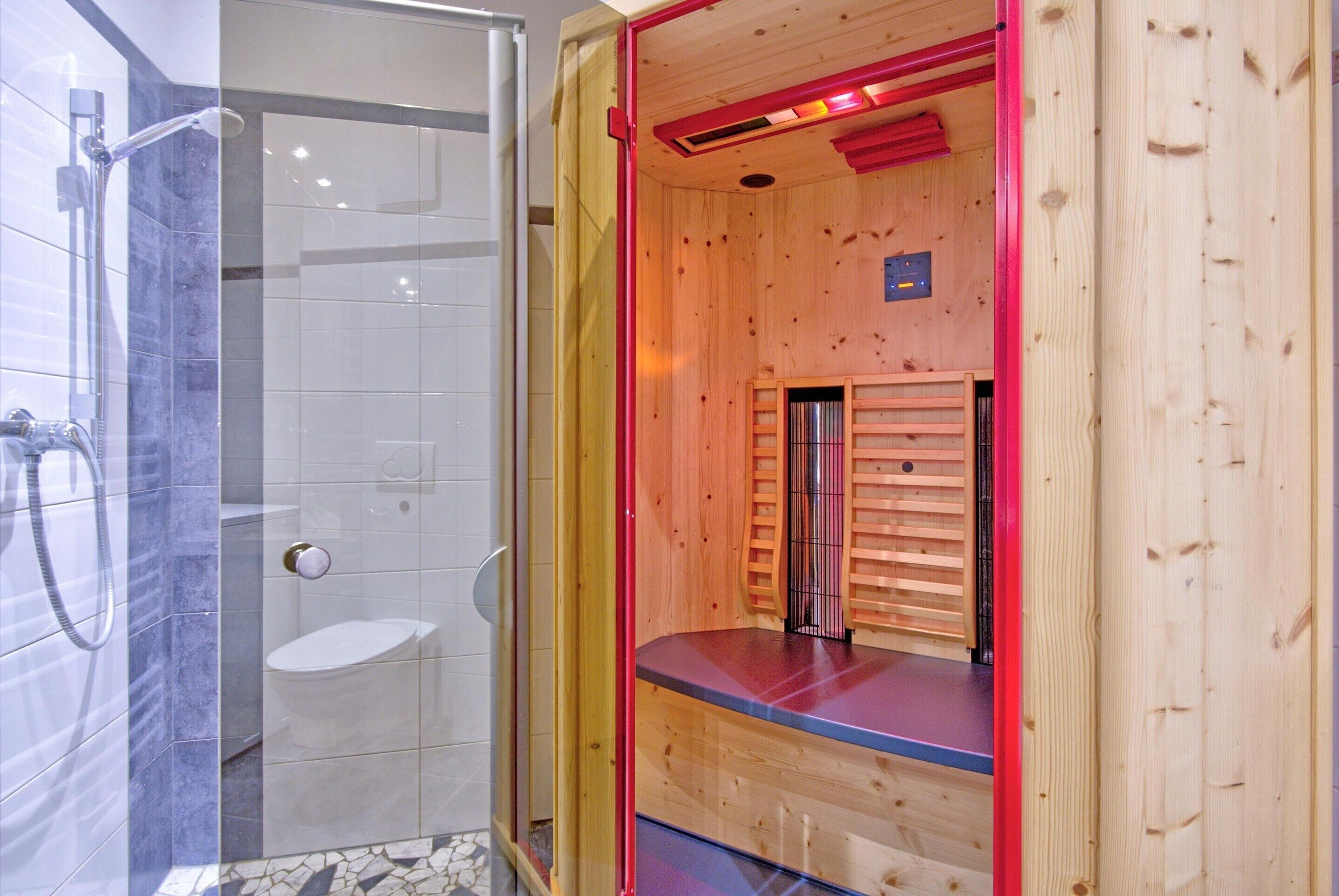 Een sauna met een glazen wand, een houten bank en een douchegedeelte.