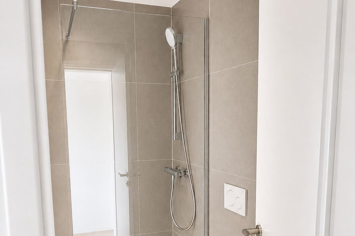 Ein modernes Badezimmer mit Dusche, Toilette und einer Tür zu einem anderen Raum.