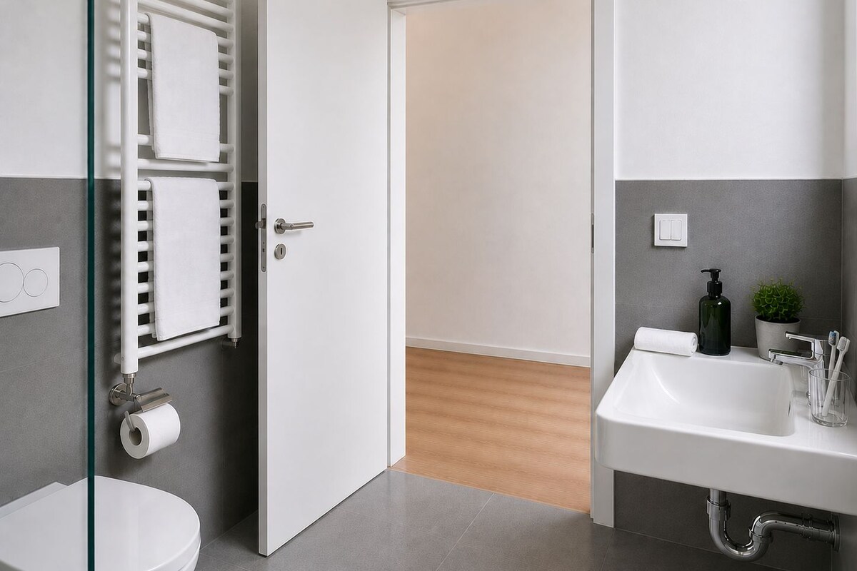 A modern bathroom with a toilet, a glass shower enclosure, a sink, and a towel rack.