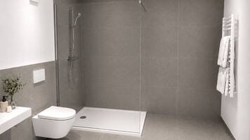 Un baño moderno con ducha, inodoro y lavamanos blanco.