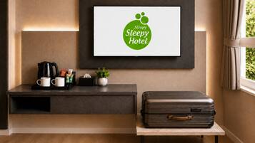A hotel room with a framed sign, a coffee station, a suitcase, and a window with curtains.