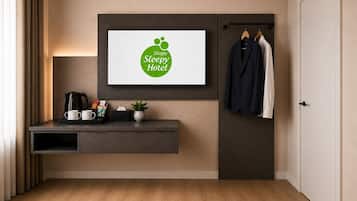Hotelkamer met een lijst met logo, een koffiehoek, een kapstok en een deur.