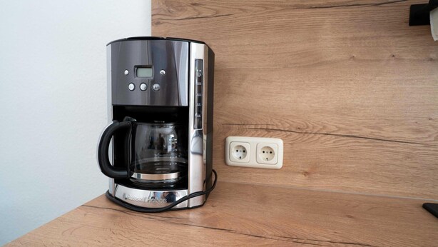 A coffee maker on a wooden countertop with a power outlet nearby. - Komfortable Ferienwohnung mit Terrasse; Bensersiel (Esens)