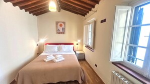 A bedroom with a wooden ceiling, a bed with white linens, a radiator, and a window with open shutters. - Owl Palace, Royal Owl in Center Town (Lucca)