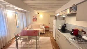 Un espacio habitable compacto con kitchenette, comedor y sofá.