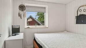 Een slaapkamer met een bed, een bureau, een raam en een decoratie aan de wand.