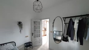 Un dormitorio con cama, cómoda, espejo y perchero.