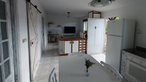 Una cocina moderna con una isla central, armarios blancos y una zona de comedor con una mesa blanca.