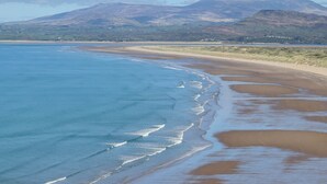 A coastal landscape with a sandy beach and a mountain range in the background. - Noddfa Country House (Harlech)