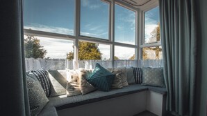 A corner seating area with a view of the outdoors, a white fence, and a clear sky. - Noddfa Country House (Harlech)