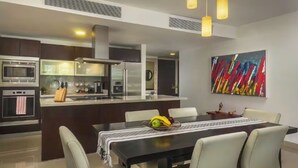 A modern kitchen with a central island, dining table, and chairs.
