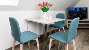 A modern dining area with a white table, teal chairs, and a vase of red tulips. - Gemuetliche Ferienwohnung im Obergeschoss, Bensersiel (Esens)