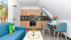 A modern kitchen with wooden cabinets, a built-in oven, and a dining area with a table and chairs. - Gemuetliche Ferienwohnung im Obergeschoss, Bensersiel (Esens)