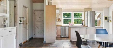 A modern kitchen with wooden cabinets, a dining area with a table and chairs, and a large window providing natural light.