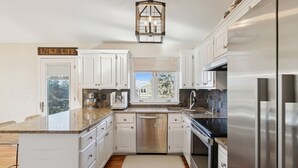 A modern kitchen with white cabinets, stainless steel appliances, and a granite countertop.