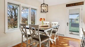 A dining area with a wooden table and chairs, a hanging light fixture, and a door with a sign that reads "LIFE".