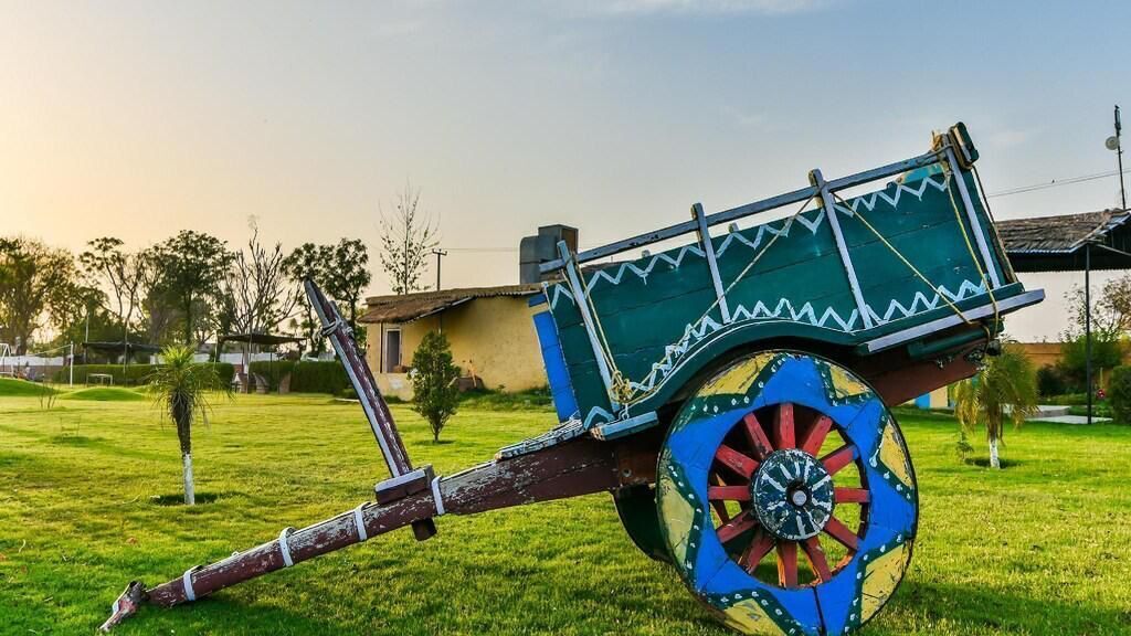 Un carrito colorido con un diseño decorativo, situado sobre un campo cubierto de hierba.